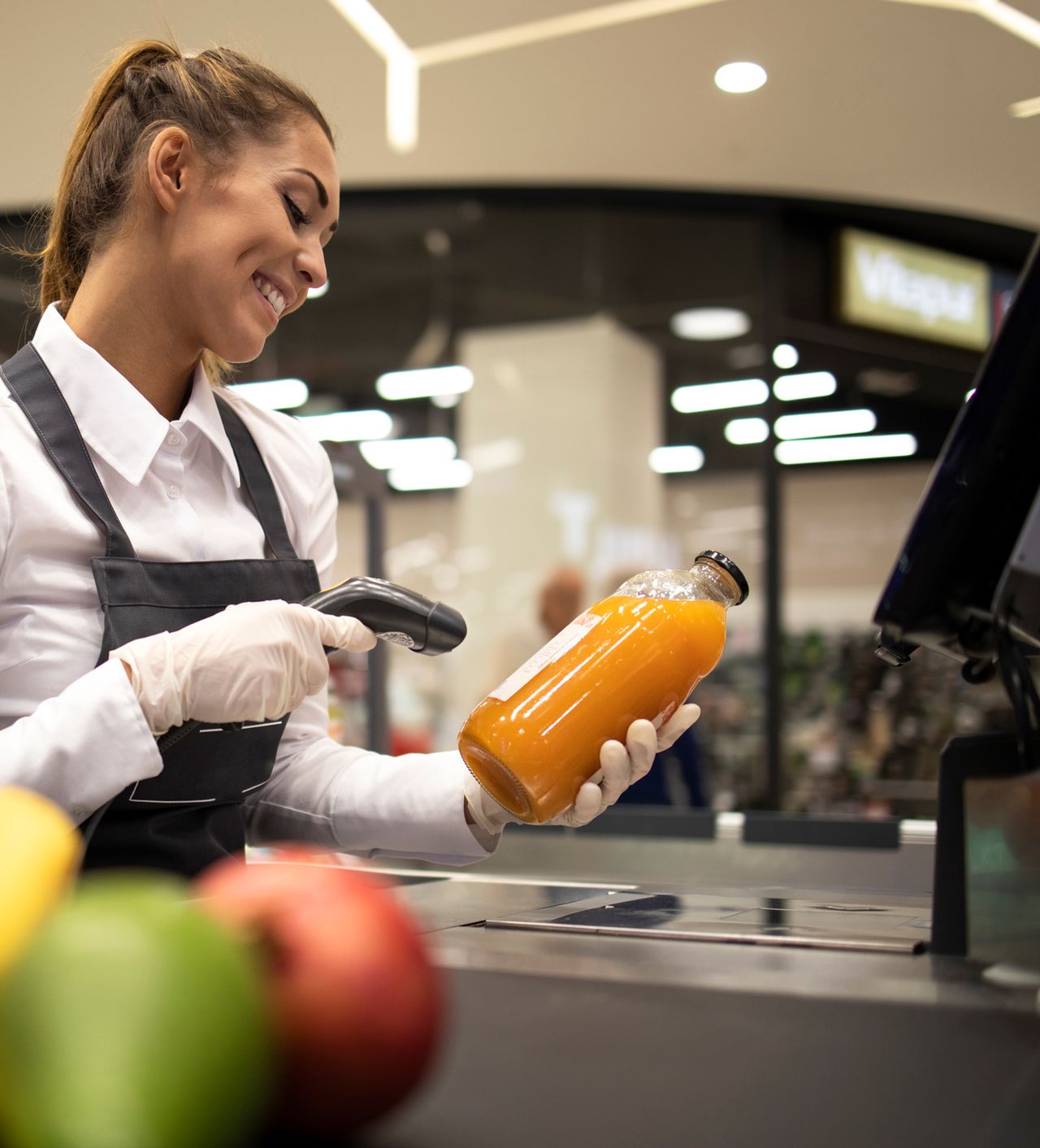 Cajera sonriendo mientras escanea un producto en un supermercado