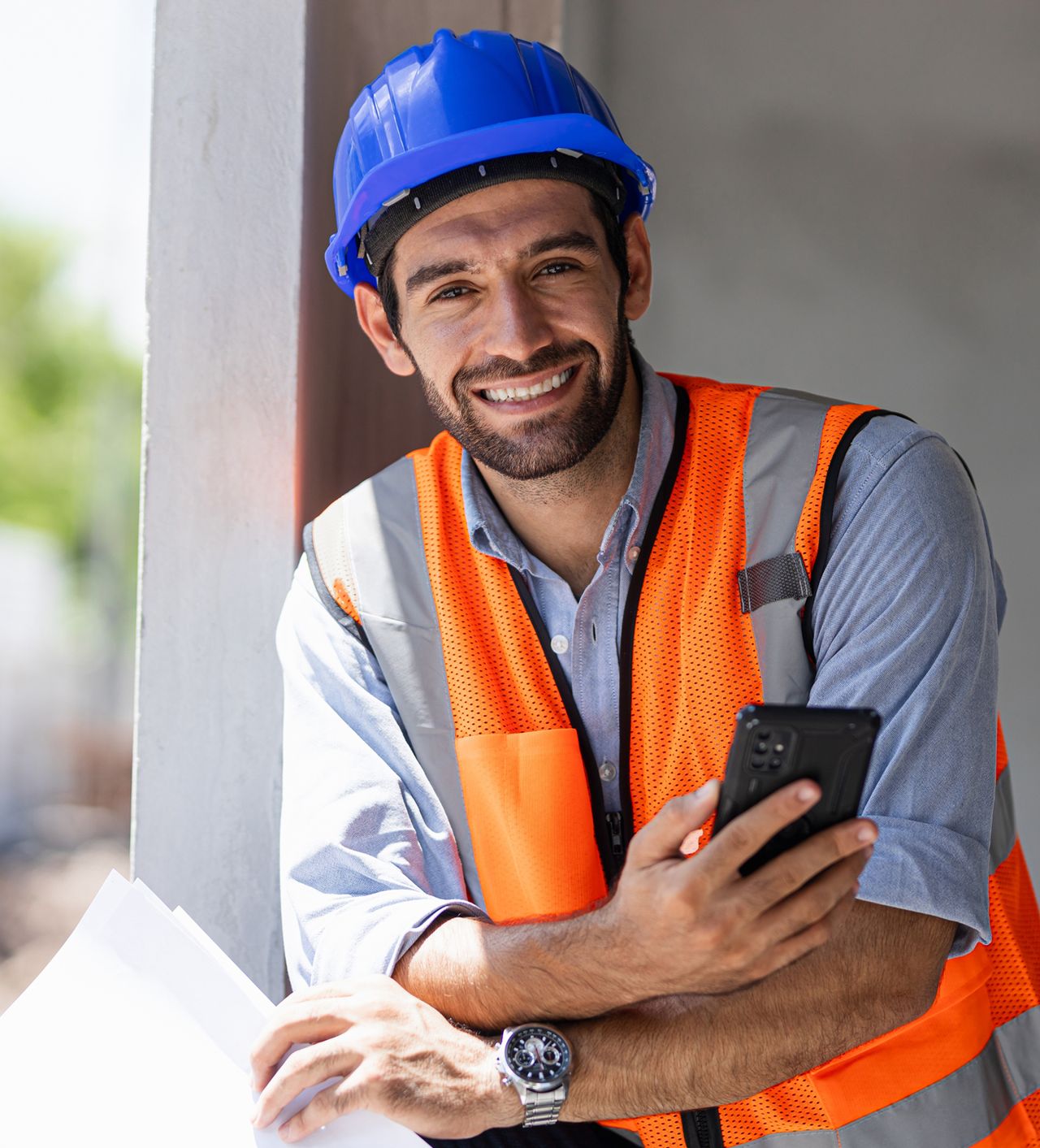 Trabajador de construcción sonriendo con casco azul y chaleco naranja