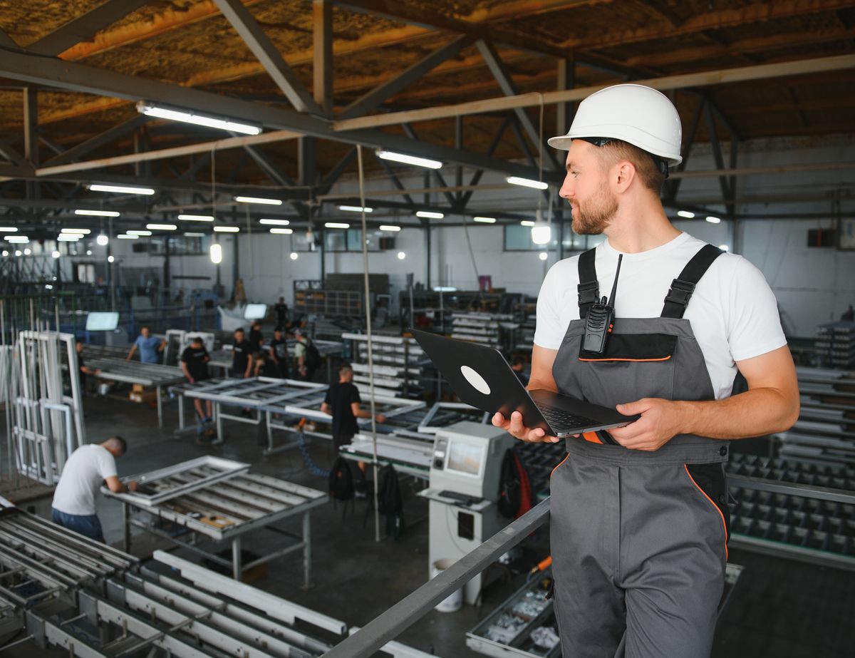 Trabajador en una planta de manufactura usando una laptop