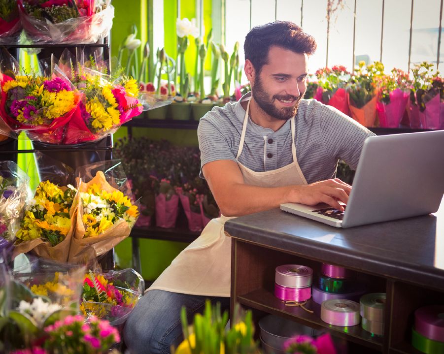 Florista gestionando pedidos y ventas online desde su laptop.